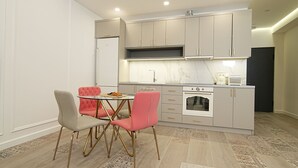 A modern kitchen with a dining area, featuring a marble backsplash, stainless steel appliances, and a small island. - Stylish 2-bedroom Apartment Next to the Republic Sqaure (Yerevan)
