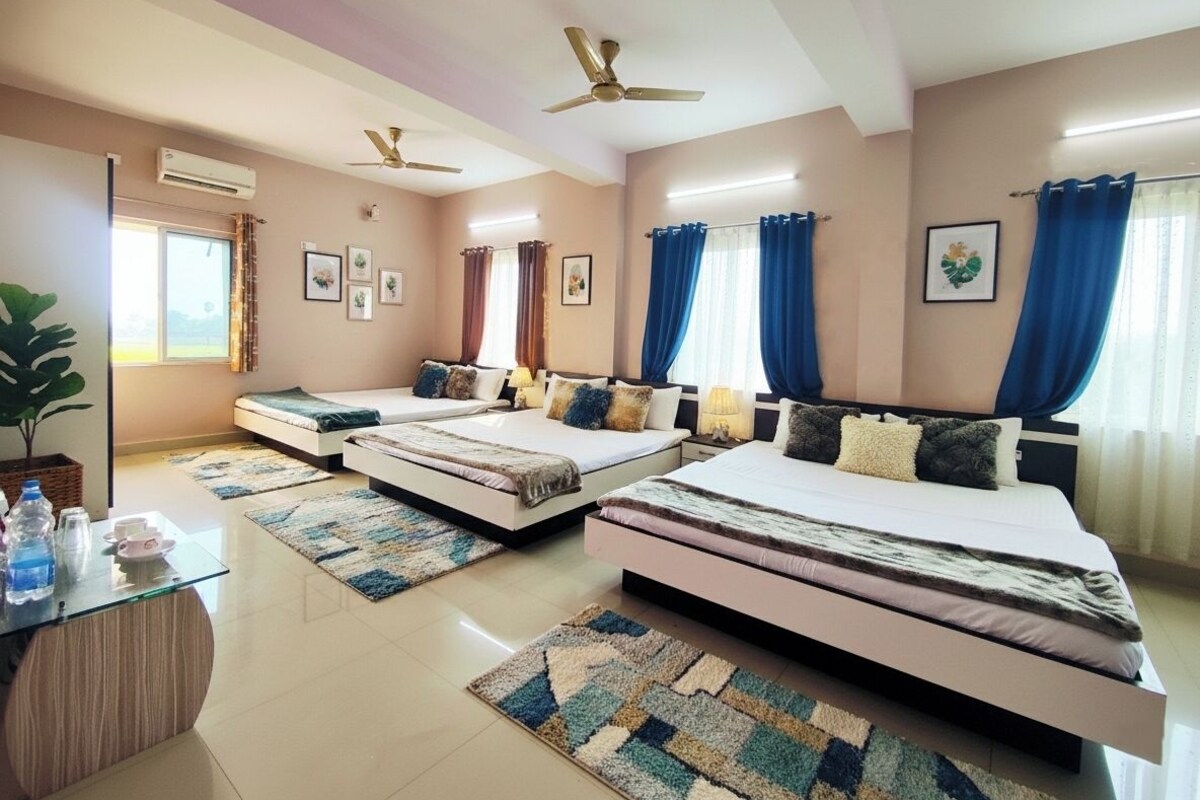 A hotel room with three beds, a desk, and a ceiling fan.