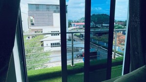 A room with a large window overlooking a parking area and buildings. - Soilsmart Haven (Abuja)
