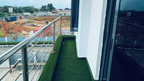 A balcony with artificial grass, a metal railing, and a view of a construction site. - Soilsmart Haven (Abuja)