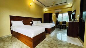 Quarto de hotel com duas camas, uma escrivaninha, uma cadeira, uma televisão e um aparelho de ar condicionado.