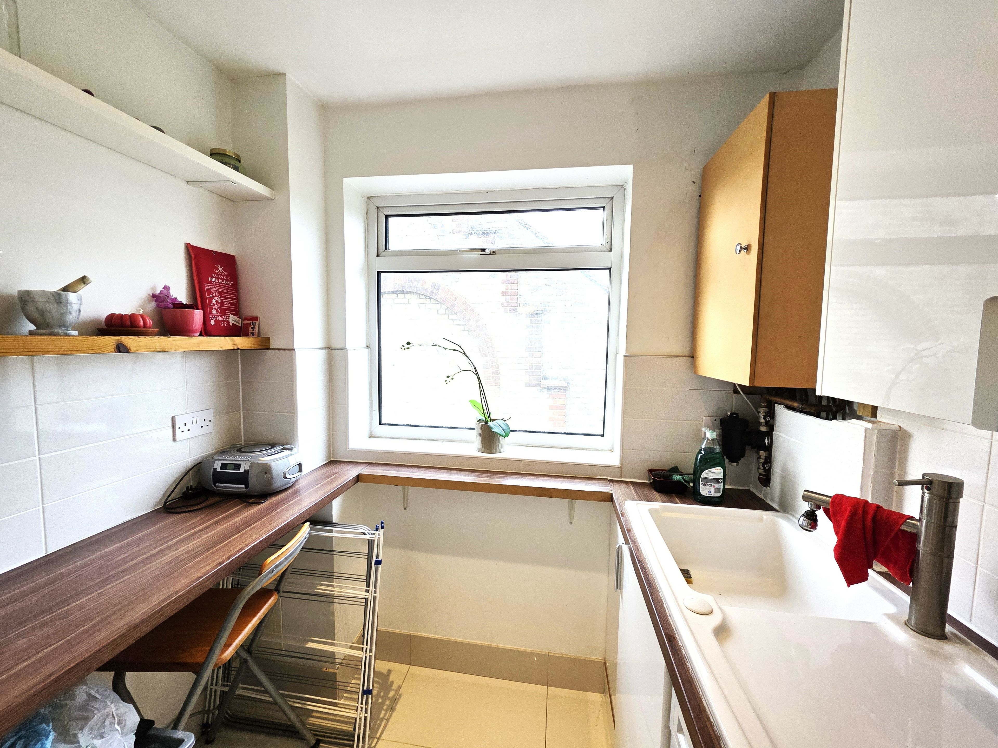 Una cocina con ventana, un fregadero, un tendedero y una encimera.