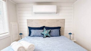 Un lit avec une couette bleue, deux oreillers, un coussin en forme d’étoile et deux serviettes enroulées.