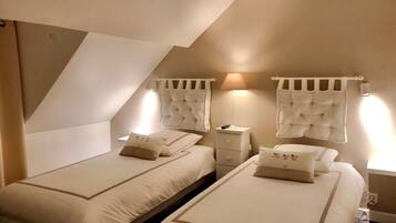Een kamer met twee bedden, elk voorzien van een hoofdbord, nachtkastjes en lampen.