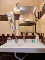 Un baño con lavamanos blanco, un espejo, toallero y un aparato TCM.