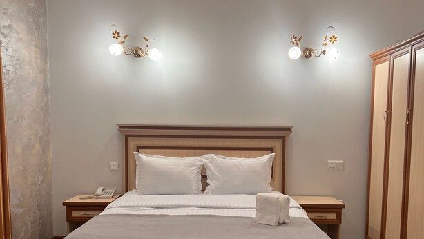 Un dormitorio con una cama grande, mesitas de noche, un armario y lámparas fijadas a la pared.