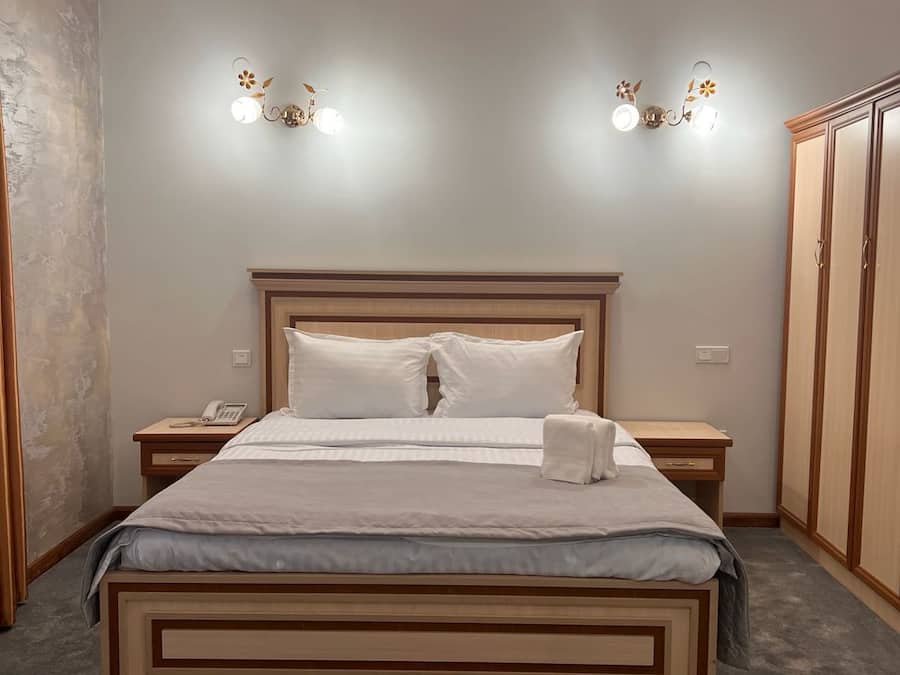 Un dormitorio con una cama grande, mesitas de noche, un armario y lámparas fijadas a la pared.