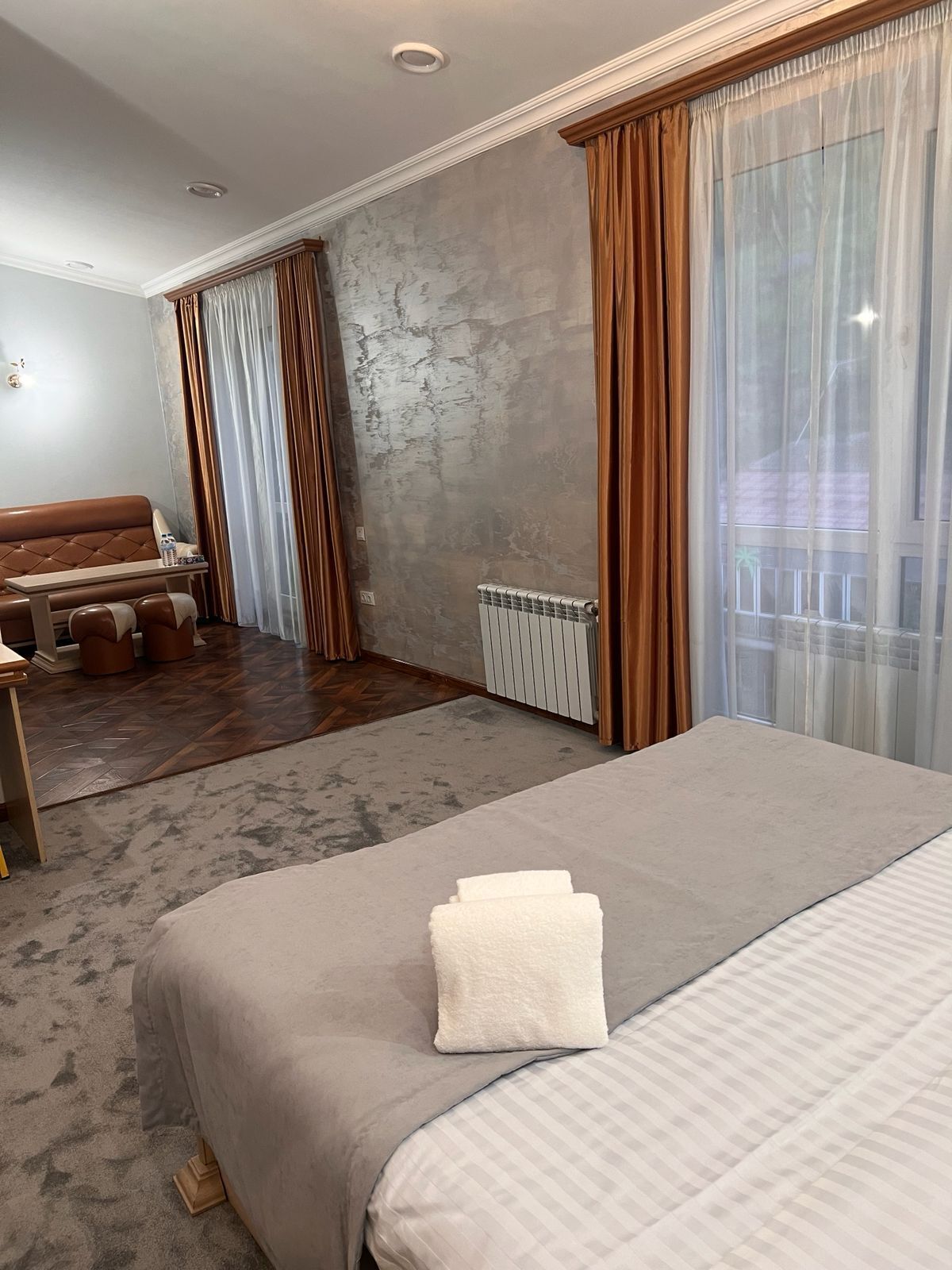 A hotel room with a bed, a sofa, a table, and a radiator.