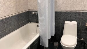 Un baño con bañera, inodoro y cortina de ducha.