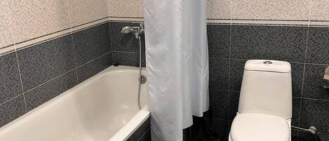 A bathroom with a bathtub, toilet, and shower curtain.