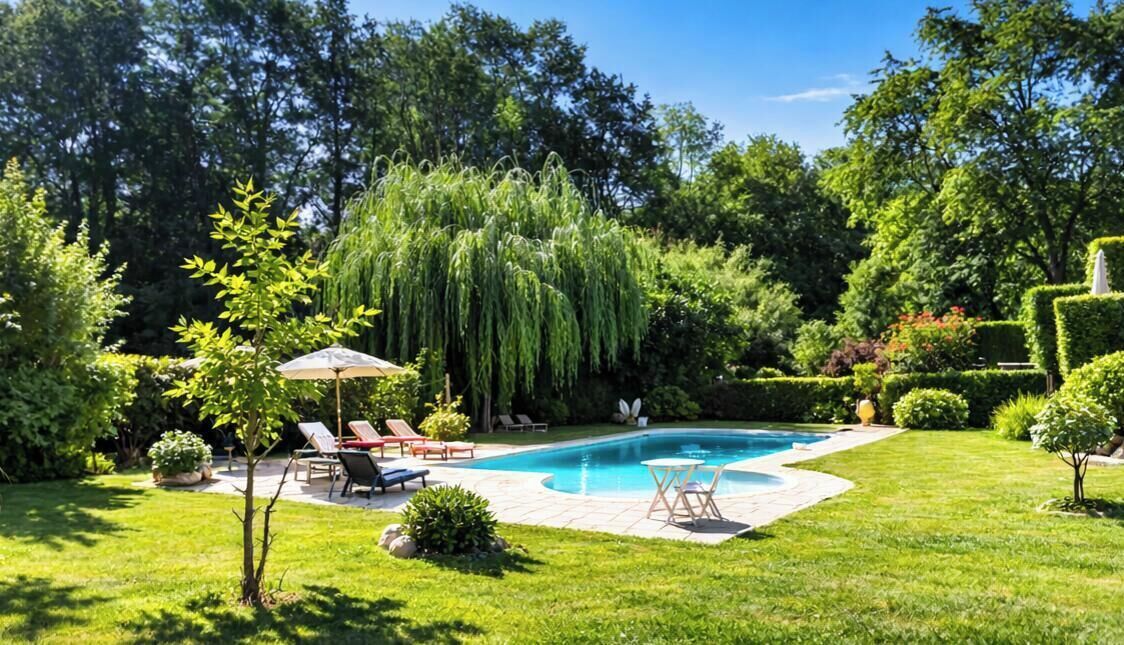 A backyard with a swimming pool, lounge chairs, and a small table.