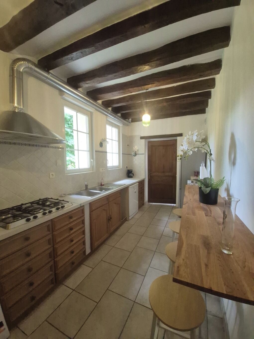 A kitchen with a gas stove, wooden cabinets, a sink, and a window.