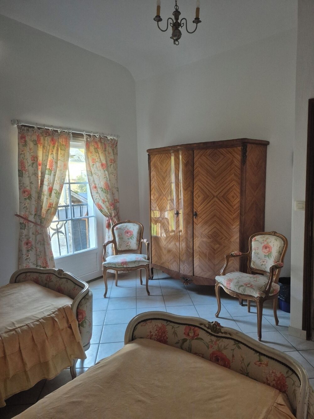 A room with two beds, a wooden wardrobe, and two chairs.