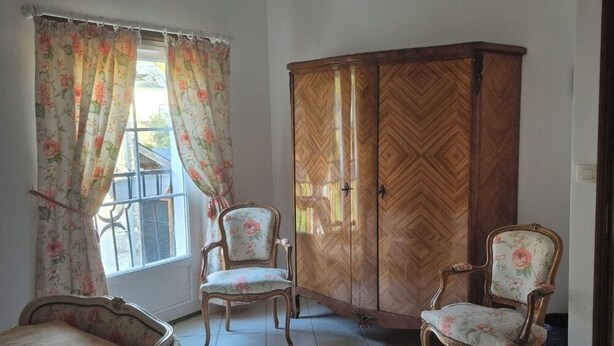 Una habitación con dos camas, un armario de madera y dos sillas.