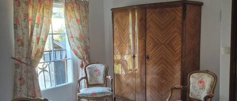 A room with two beds, a wooden wardrobe, and two chairs.