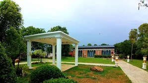 A gazebo, a brick building, and a pathway in a landscaped garden. - THE AIYARARIN RESORT (Phitsanulok)