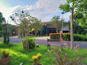 A landscaped garden with a bench, potted plants, and a building entrance. - THE AIYARARIN RESORT (Phitsanulok)