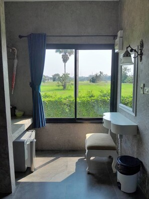A room with a large window, a white sink, a bench, and a trash bin. - THE AIYARARIN RESORT (Phitsanulok)