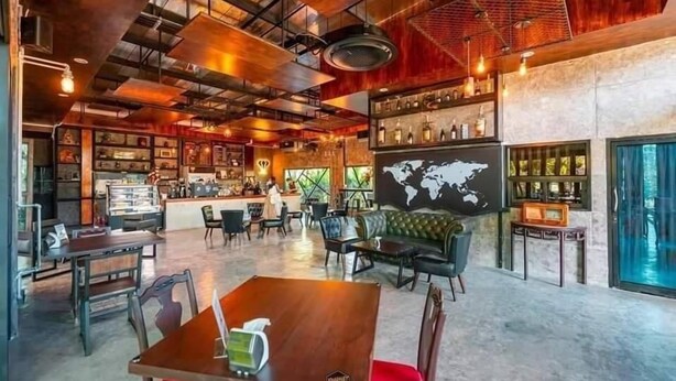 A spacious cafe with a bar area, seating, and a world map on the wall. - THE AIYARARIN RESORT (Phitsanulok)