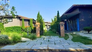 A residential driveway leading to a house with a gated entrance, surrounded by well-maintained hedges and a clear sky. - THE AIYARARIN RESORT (Phitsanulok)