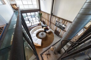 Een modern interieur met een glazen balustrade, een rond zitgedeelte en een grote metalen kolom.