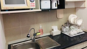 A kitchen with a microwave, toaster, sink, dish rack, and various utensils. - Room-supalai City Resort Changwattana (Pak Kret)