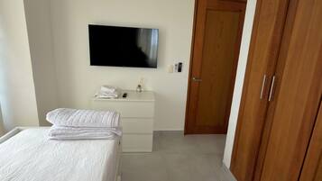 Een slaapkamer met een bed, een dressoir, een televisie en een kast.