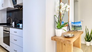 A modern kitchen with white cabinets, a built-in oven, and a stainless steel range hood. - Silva's House, a Home in Madeira (Ponta do Sol)