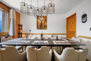 Un espace repas avec une longue table, des chaises et un lustre.