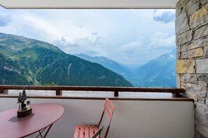 A balcony with a table and chair, overlooking a mountainous landscape. - High-End Apartment in La Rosière 1850, 5 Rooms for 10 Guests, Ski-In/Ski-Out (Montvalezan)