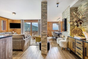 A modern living room with a fireplace, a dining area, and a kitchen with a wooden cabinet. - High-End Apartment in La Rosière 1850, 5 Rooms for 10 Guests, Ski-In/Ski-Out (Montvalezan)