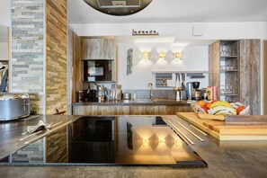 A modern kitchen with a central island, built-in appliances, and a stone accent wall. - High-End Apartment in La Rosière 1850, 5 Rooms for 10 Guests, Ski-In/Ski-Out (Montvalezan)