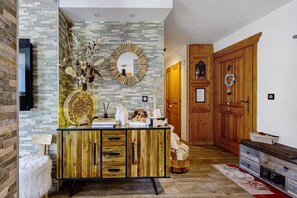 A modern interior with a stone wall, a wooden cabinet with drawers, a mirror, and a wooden door labeled 'HOME'. - High-End Apartment in La Rosière 1850, 5 Rooms for 10 Guests, Ski-In/Ski-Out (Montvalezan)