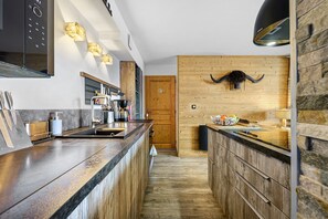 A modern kitchen with a central island, wooden accents, and a rustic wall decor. - High-End Apartment in La Rosière 1850, 5 Rooms for 10 Guests, Ski-In/Ski-Out (Montvalezan)