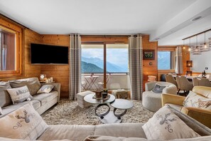 A cozy living room with a large window, wooden walls, a flat-screen TV, and comfortable seating. - High-End Apartment in La Rosière 1850, 5 Rooms for 10 Guests, Ski-In/Ski-Out (Montvalezan)