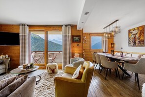 A modern living room with a large window, a dining area, and a view of mountains. - High-End Apartment in La Rosière 1850, 5 Rooms for 10 Guests, Ski-In/Ski-Out (Montvalezan)