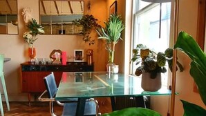A dining area with a glass table, chairs, and a large green plant.