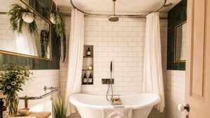 A bathroom with a freestanding bathtub, a mirror, a towel rack, and a shower curtain.