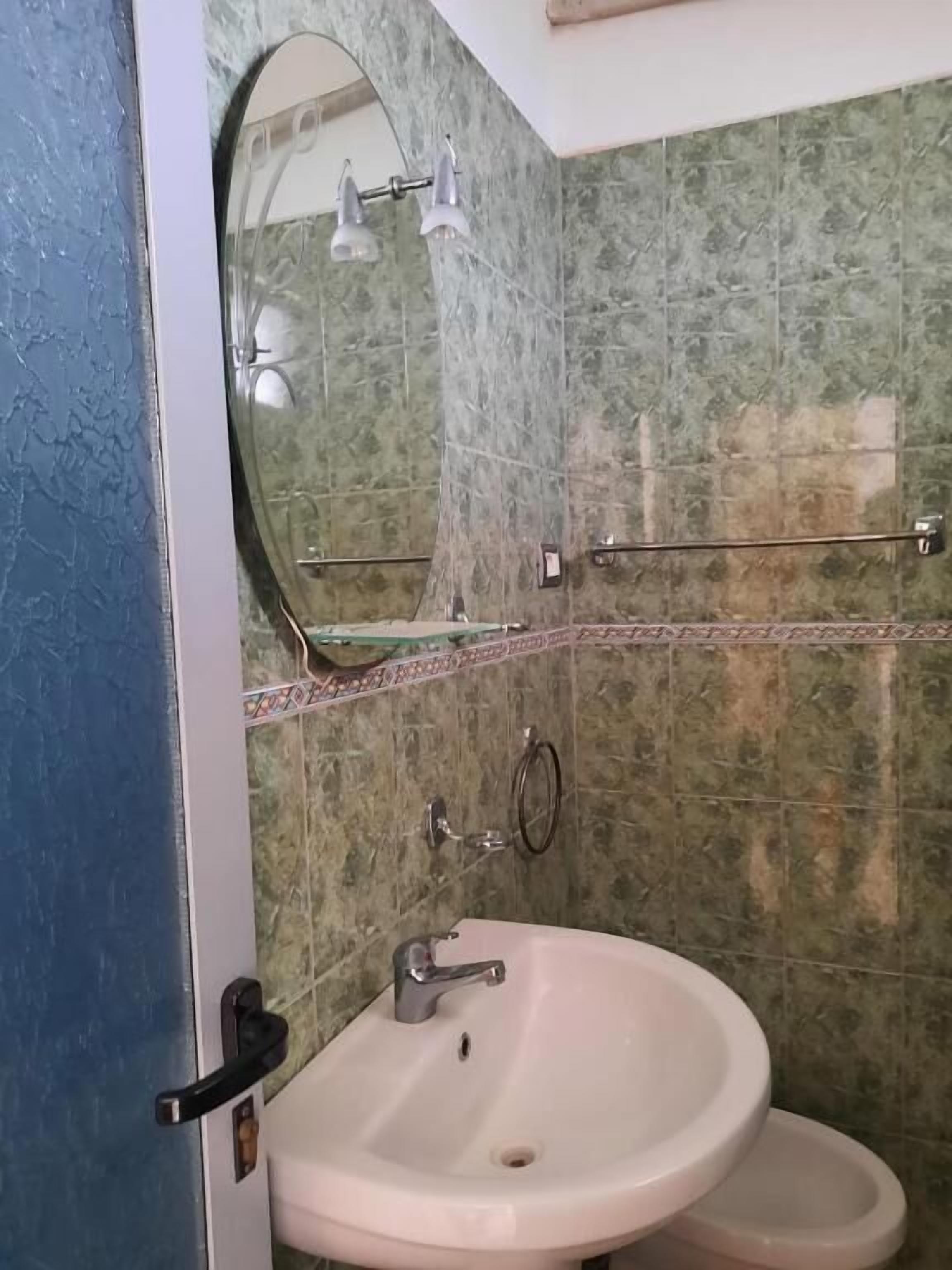 A bathroom with a sink, mirror, and tiled walls.
