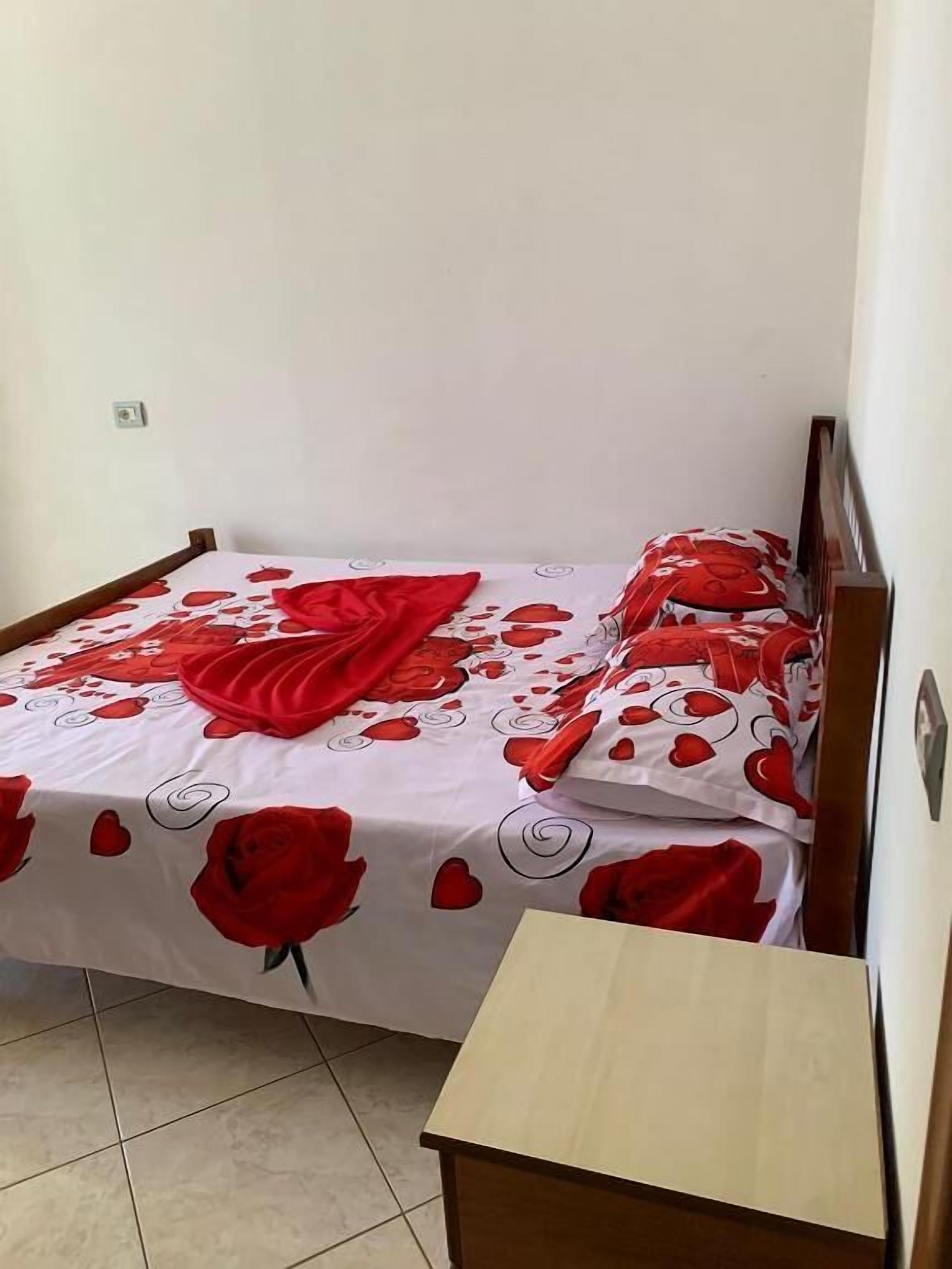 A bed with a floral bedspread, a wooden headboard, and a bedside table.