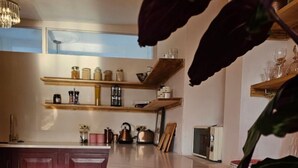 A modern kitchen with marble countertops, wooden shelves, and a large island. - 3 Bedroom Home on the Beautiful Trinity Square (Kent)