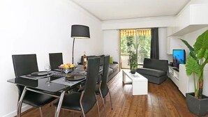 Un salon moderne comprenant un coin repas, un canapé, une table basse et un téléviseur.