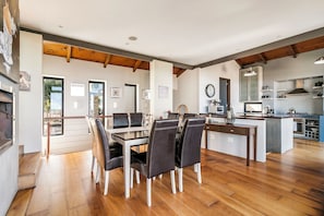 A spacious dining area with a wooden floor, a central island with a sink, and a kitchen in the background.