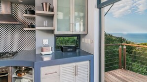 Una cocina moderna con horno empotrado, panificadora y vistas al océano.