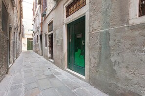 A narrow alleyway with stone pavement, flanked by old buildings with wooden shutters and a green door. - Apartment 'Venezia Baroque Charm' with Wi-Fi and Air Conditioning (Venice)