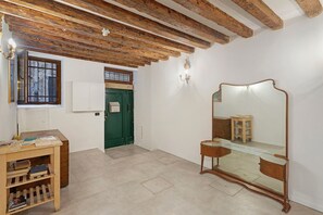 A room with a wooden ceiling, a mirror, a green door, and a small wooden table with books. - Apartment 'Venezia Baroque Charm' with Wi-Fi and Air Conditioning (Venice)