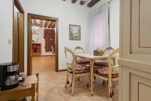 Un coin repas avec une table et des chaises, une machine à café et un tableau accroché au mur.