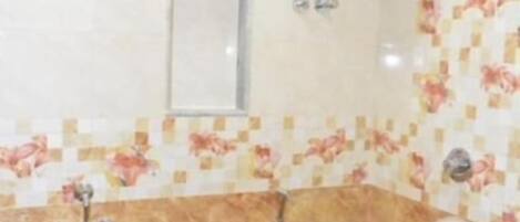 A bathroom with a toilet, a sink, a shower, and a hand dryer. There are two buckets on the floor.