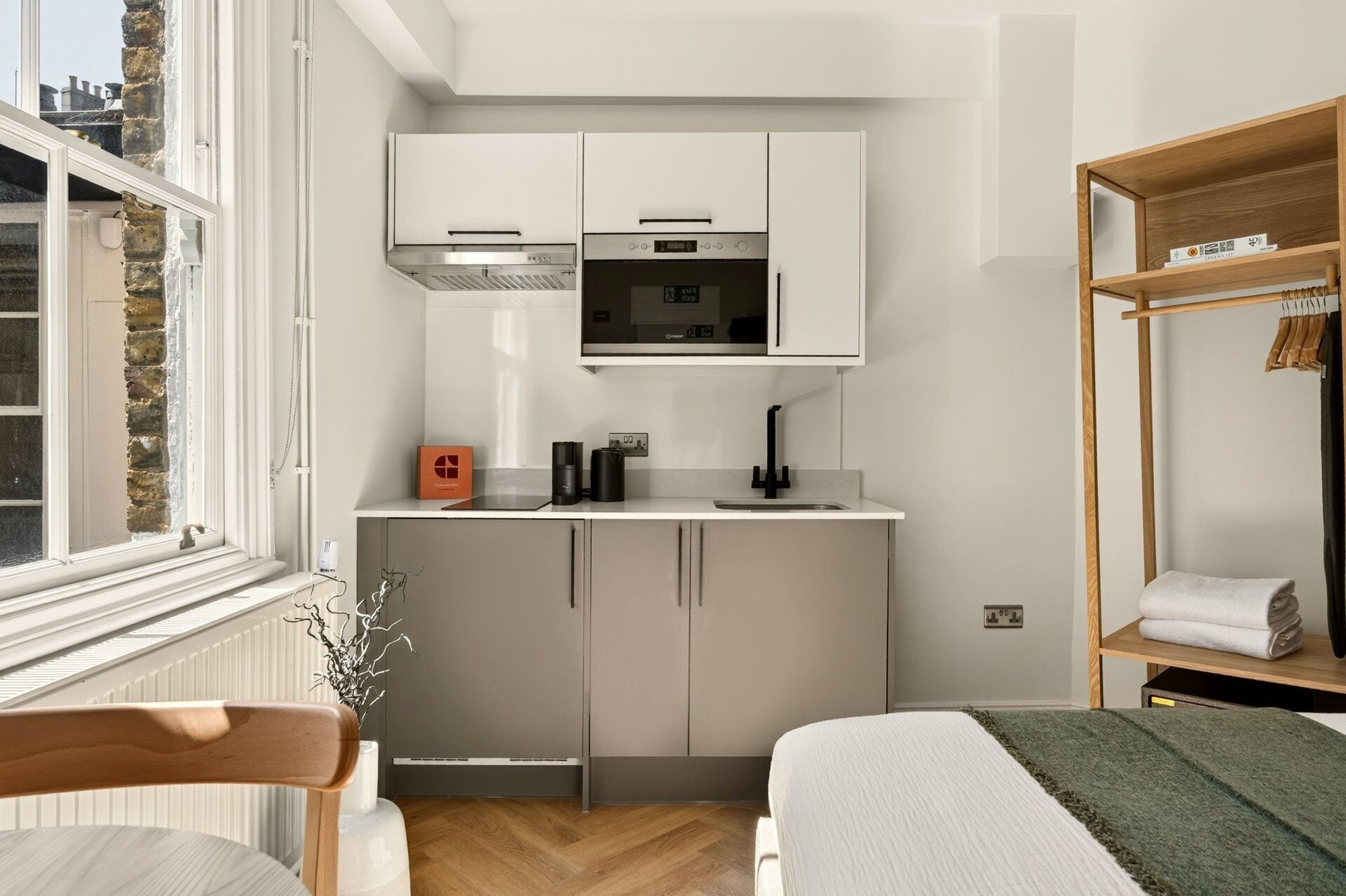 A compact kitchenette with a microwave, oven, and white cabinets.