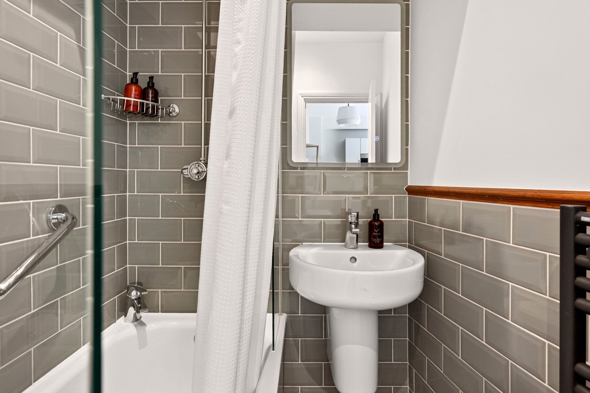 A bathroom with a bathtub, a sink, and a mirror.